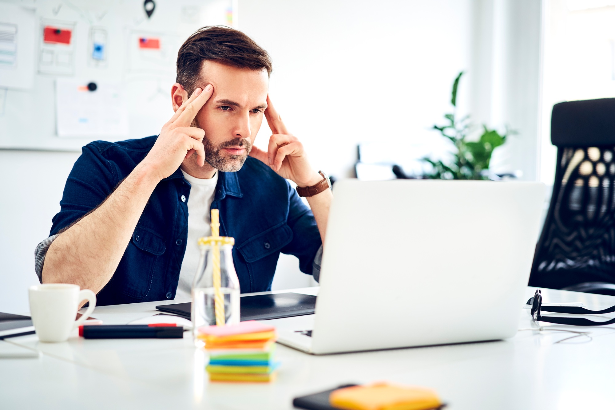 Focused businessman working on laptop at desk in office